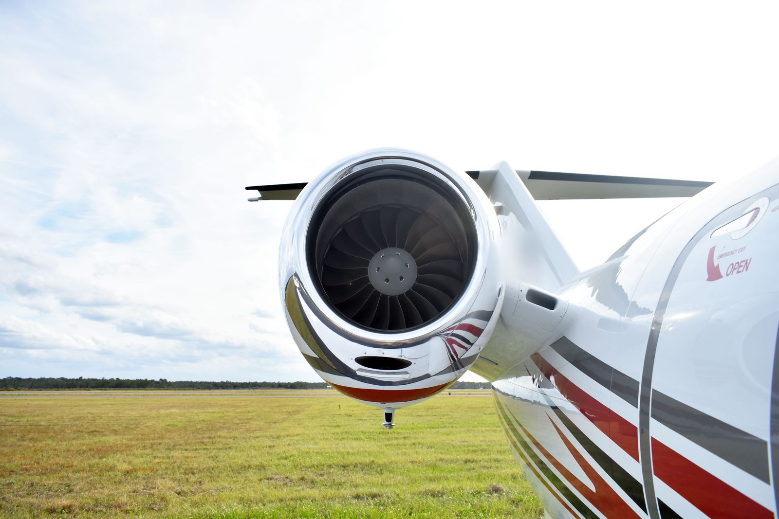 Close-up of a business jet's polished engine nacelle and wing root against a soft cloudy sky