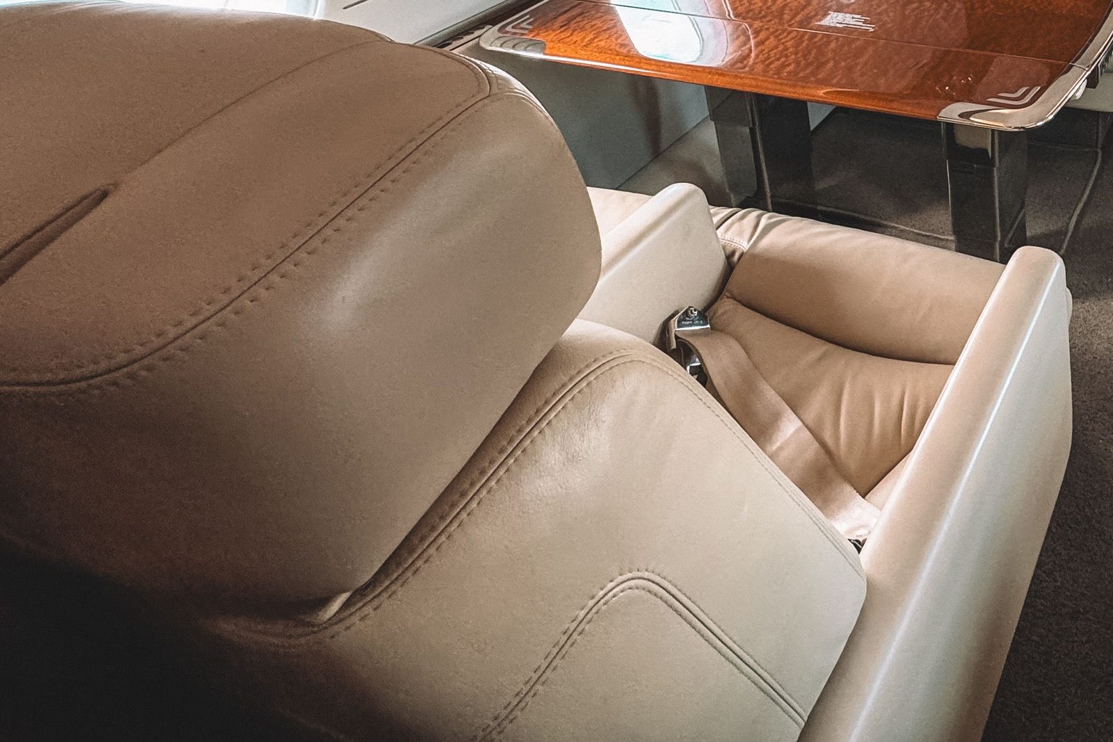Close detail of a cream leather seat with stitched seams in a private jet cabin